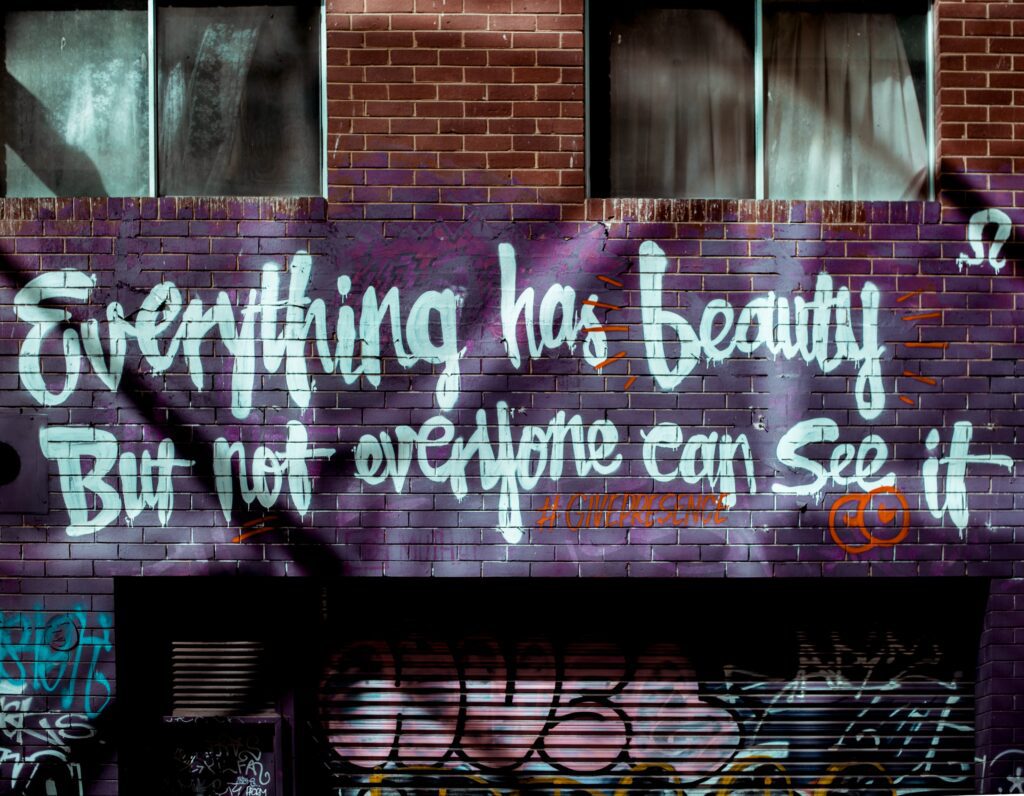 A purple wall with graffiti about beauty